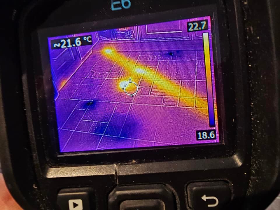 IGM Plumbing and Heating thermal scan showing a bright heat signature from an underfloor heating pipe beneath floor tiles.